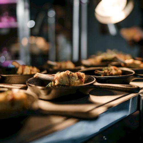 The image shows several plates of food under warm lighting, possibly in a restaurant or kitchen setting.